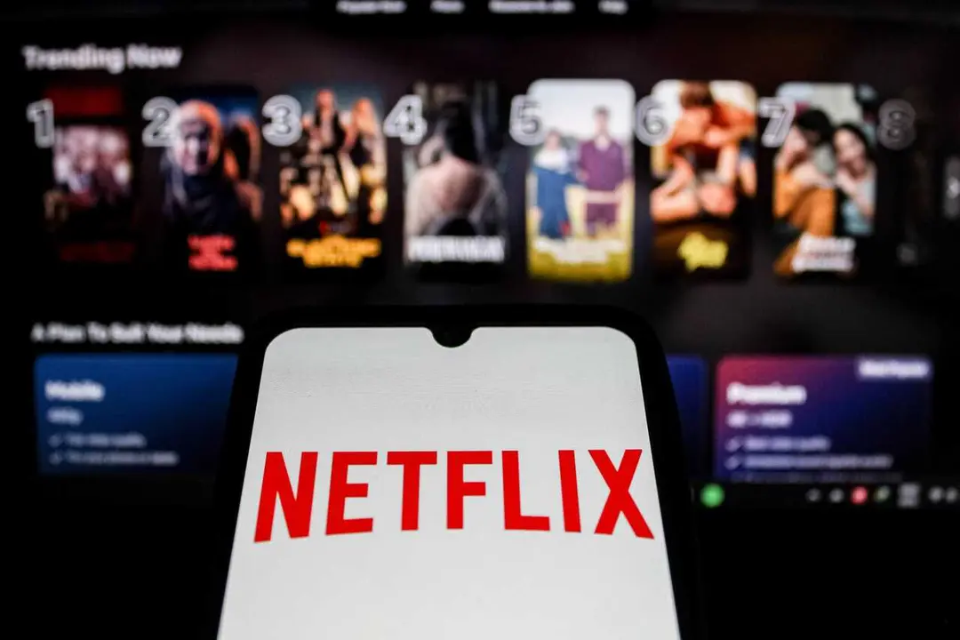In this photo illustration, the Netflix Logo displayed on a smartphone screen with Netflix website in the background.
