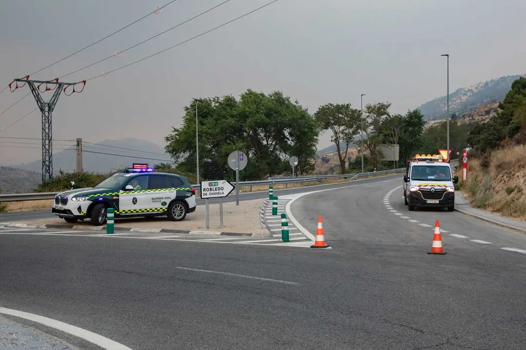 Veh&iacute;culos de la guardia civil vigilan la carretera cortada durante las labores de extinci&oacute;n del incendio forestal