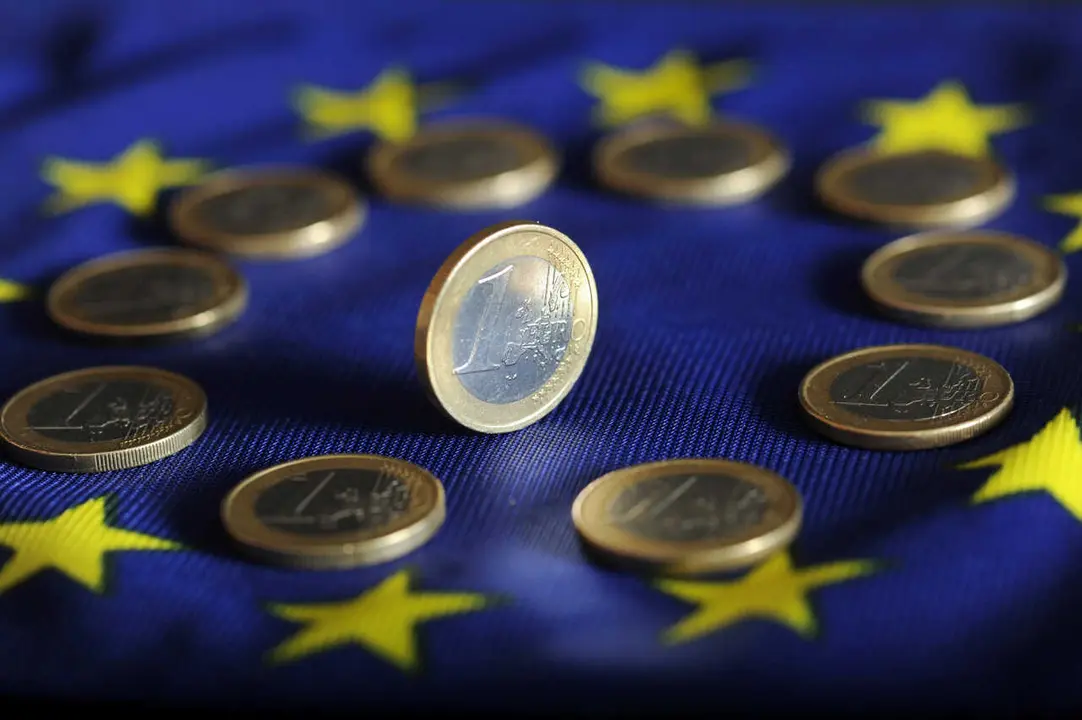 Archivo - Monedas de euro sobre una bandera europea