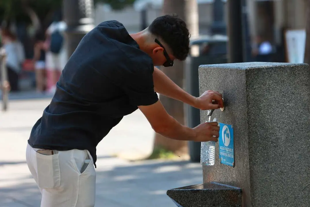 Una persona se refresca en una fuente, en Sevilla (Andaluc&iacute;a, Espa&ntilde;a). 