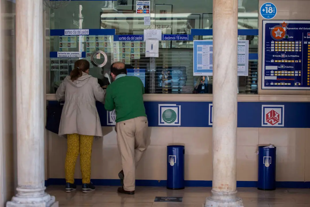Archivo - Dos personas compran loter&iacute;a en una Administraci&oacute;n.
