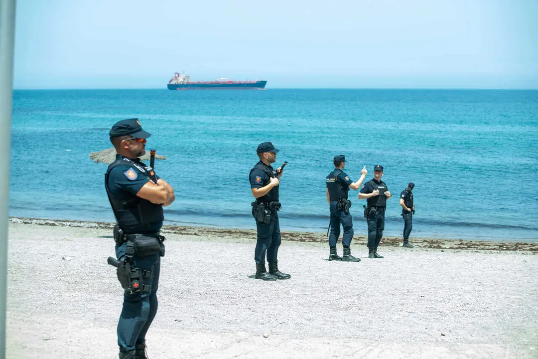 Spanish National Police officers stand around a large group of migrants near the Temporary Stay Centre for Immigrants (CETI).