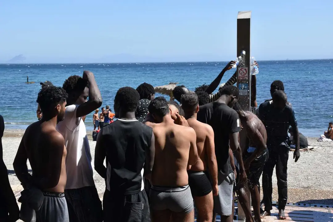 Varias personas se asean en las duchas p&uacute;blicas, en la playa del Trampol&iacute;n, a 5 de agosto de 2026, en Ceuta (Espa&ntilde;a). La Polic&iacute;a Nacional ha comenzado el proceso de triaje de los migrantes que permanecen en Ceuta, 'unos 2.500' seg&uacute;n informaciones de la De