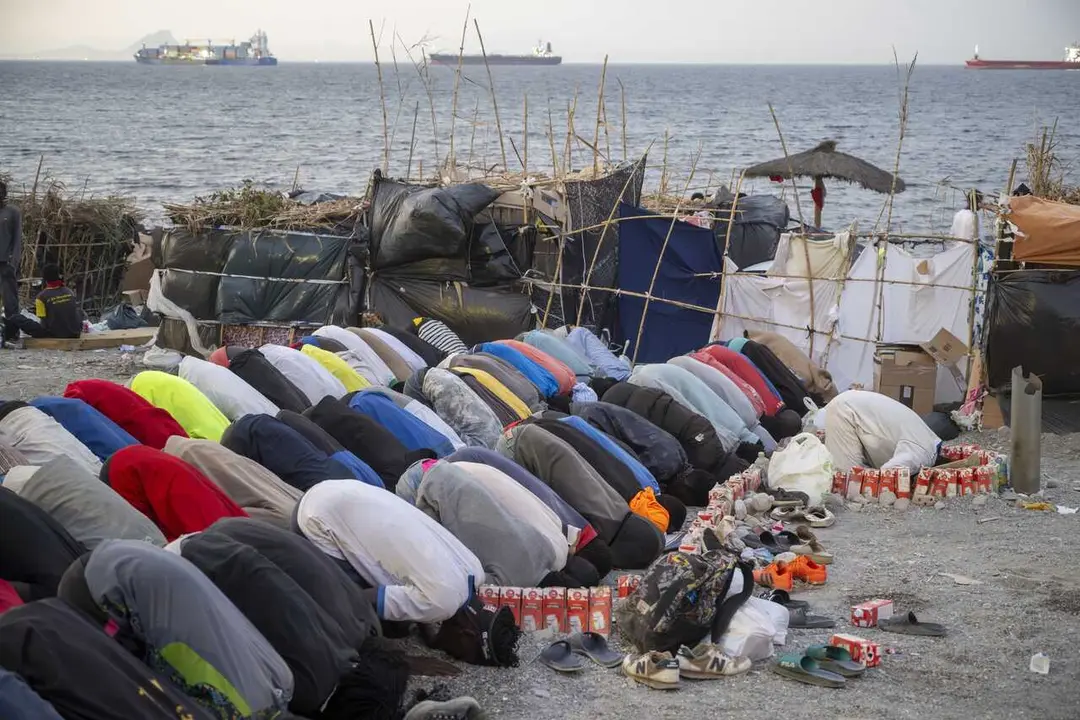 Varios inmigrantes rezan en una playa de Ceuta.