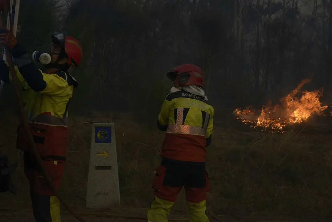 Dos bomberos durante las labores de extinci&oacute;n de un incendio forestal, la carretera nacional 525, a 15 de agosto de 2026, en O Ri&oacute;s, Ourense, Galicia (Espa&ntilde;a).