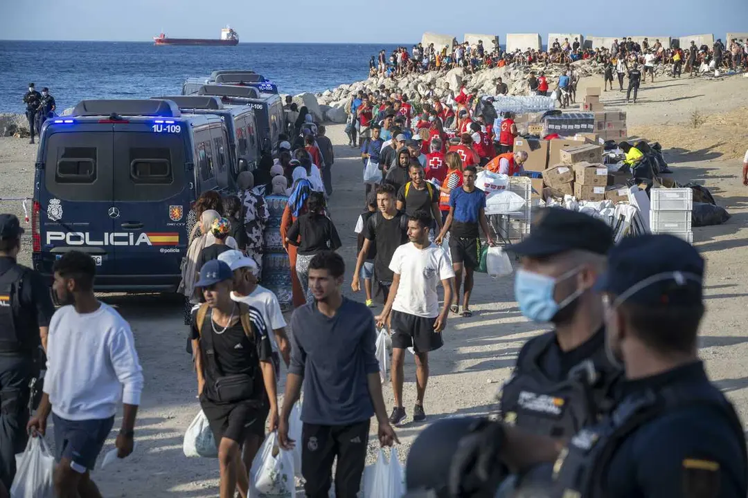 Miembros de la Cruz Roja atienden a varios inmigrantes, en la playa del Trampol&iacute;n, a 20 de agosto de 2026, en Ceuta (Espa&ntilde;a)