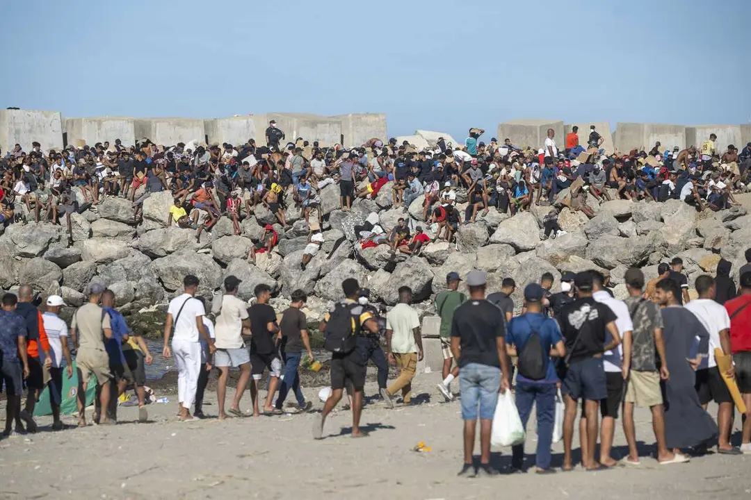 Miembros de la Cruz Roja reparten comida a los inmigrantes en una playa, a 21 de agosto de 2026, en Ceuta (Espa&ntilde;a). 