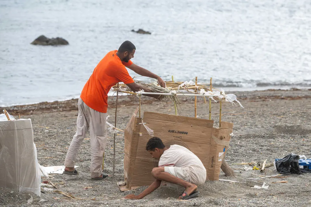 Varios migrantes vuelven a instalarse en la playa El Trampol&iacute;n durante las tareas de limpieza, a 24 de agosto de 2026, en Ceuta (Espa&ntilde;a). 