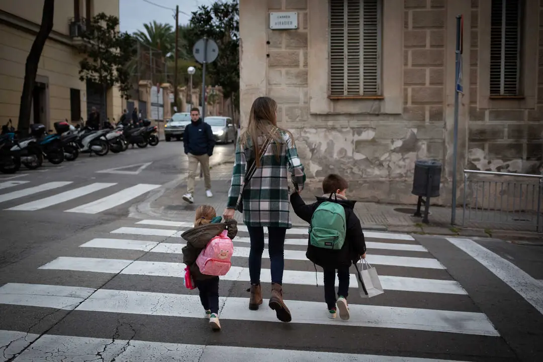Archivo - Dos ni&ntilde;as de la mano con una mujer a su llegada al primer d&iacute;a de clase presencial tras la Navidad, a 10 de enero de 2022, en Barcelona, Catalunya, (Espa&ntilde;a). 