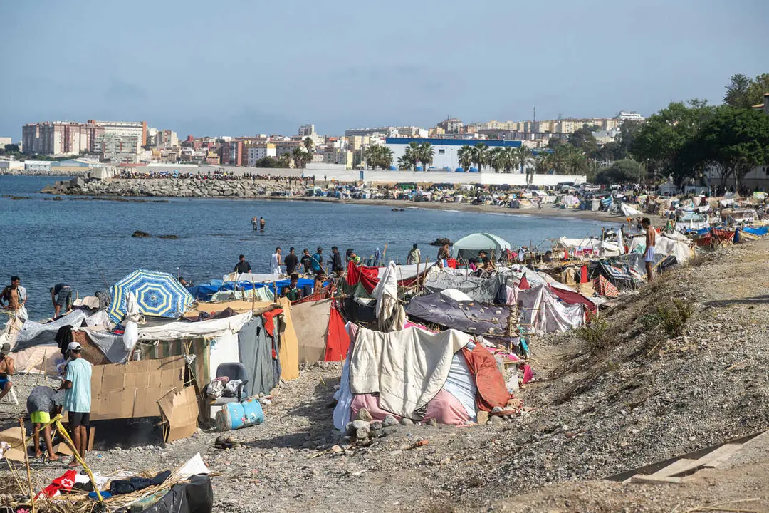 Decenas de migrantes asentados de nuevo en la playa del Trampol&iacute;n, a 31 de agosto de 2026, en Ceuta (Espa&ntilde;a). 