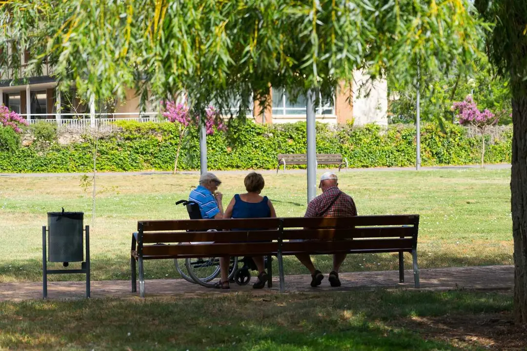 Archivo - Tres personas mayores en un banco junto a una residencia.