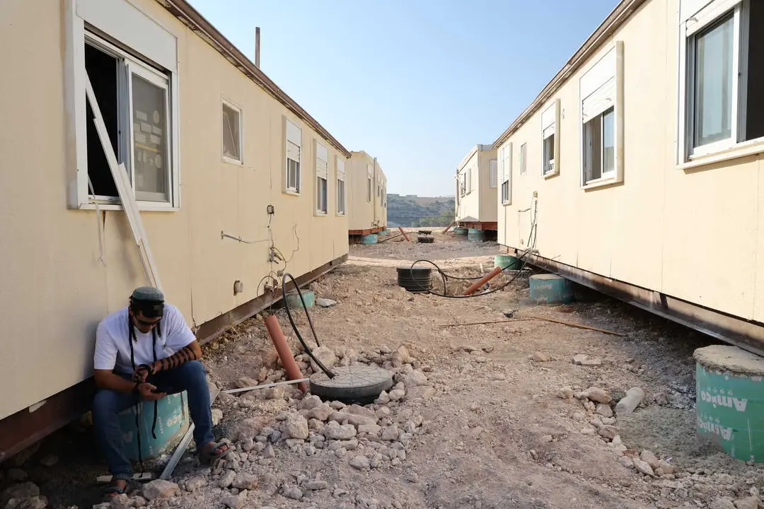 Un colono jud&iacute;o est&aacute; sentado junto a unas casas prefabricadas en el asentamiento de Ganim, en Cisjordania, el 13 de agosto de 2026.