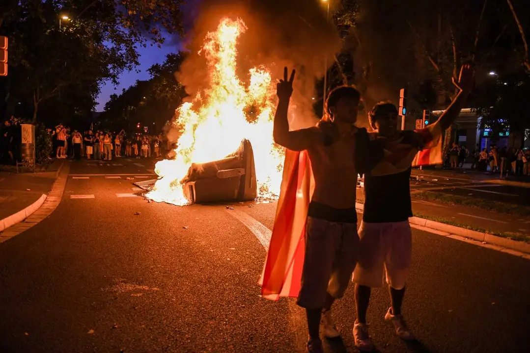 Activistas posan ante un contenedor en llamas en Barcelona durante la Diada de Catalunya