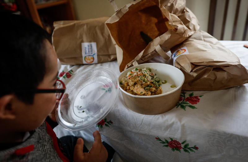  Un niño durante la comida en su casa del barrio madrileño de Carabanchel abre la tapa de un plato del menú de la ONG del chef José Andrés, en Madrid (España) a 14 de abril de 2020. - Jesús Hellín - Europa Press - Archivo 