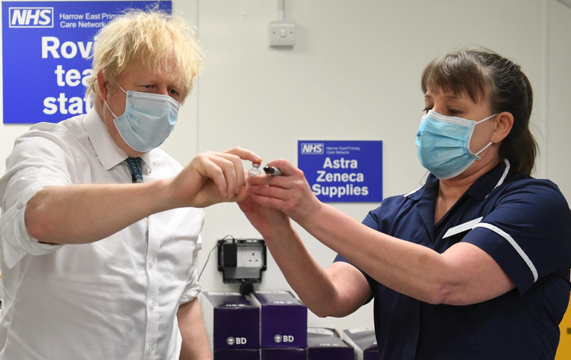  25 January 2021, United Kingdom, London: UK Prime Minister Boris Johnson (L) is shown a vial of the Oxford/Astrazeneca COVID-19 vaccine during a visit to Barnet FC's ground at The Hive, which is being used as a coronavirus vaccination centre. - Stefan Rousseau/PA Wire/dpa 