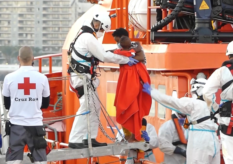  Un miembro de la Cruz Roja ayuda a bajar del barco a una mujer migrante con su niño en el puerto de Arguineguín - Europa Press 