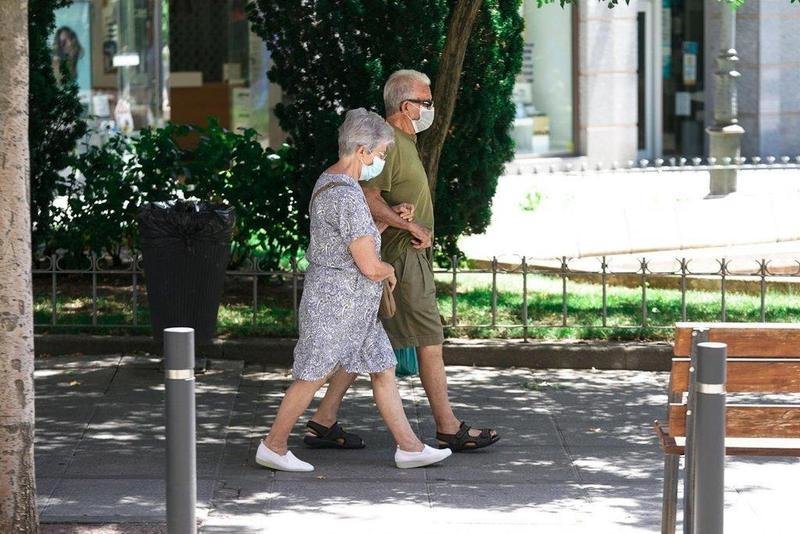  Una pareja de ancianos con mascarilla camina por la calle cogida del brazo, a 27 de julio de 2021, en Madrid, (España). - A. Pérez Meca - Europa Press 
