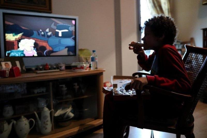  Archivo - Un niño come un trozo de pizza mientras ve la televisión en su casa, en Madrid (España) a 20 de marzo de 2020. - Jesús Hellín - Europa Press - Archivo 