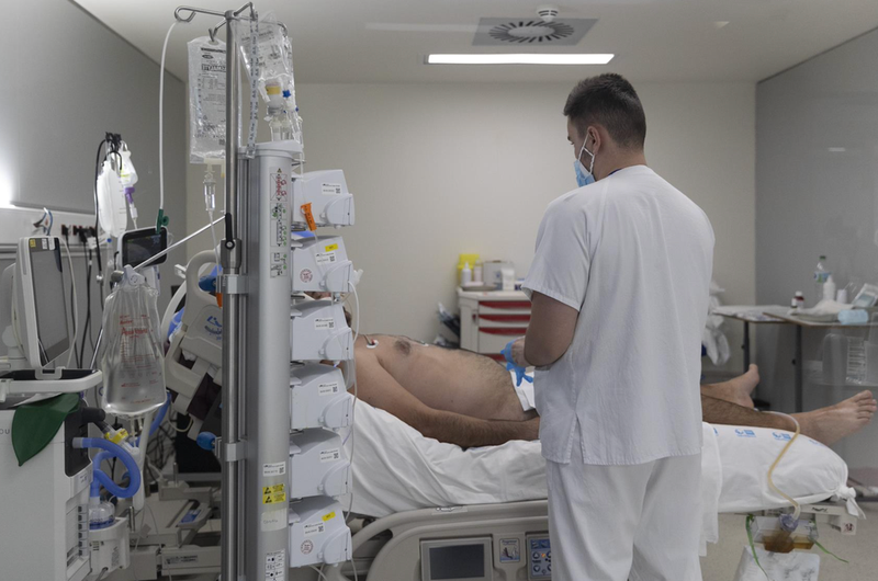 <p> Un sanitario alrededor de un paciente ingresado en la UCI del Hospital Enfermera Isabel Zendal, a 13 de enero de 2022, en Madrid (España). - Eduardo Parra - Europa Press </p>