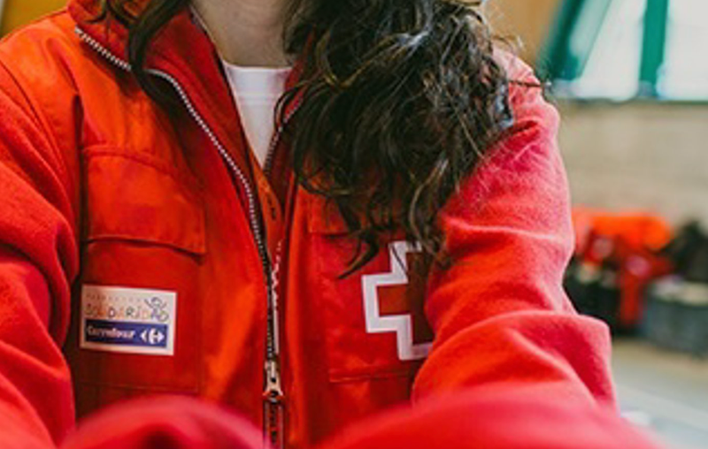 <p> Una voluntaria entrega un chaleco de Cruz Roja - FUNDACIÓN SOLIDARIDAD CARREFOUR </p>