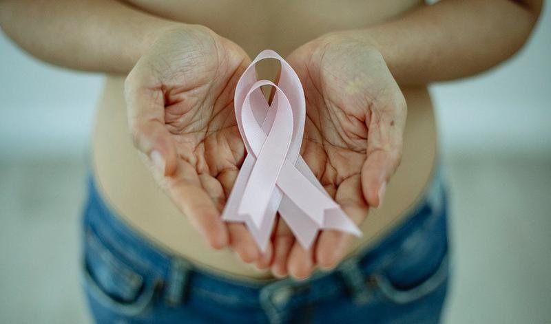 <p> Mujer portando lazos de color rosa para la concienciación sobre el cáncer de mama </p>