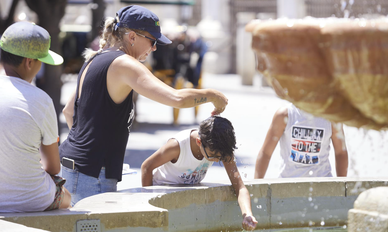 <p> Una madre le echa agua a su hijo, por la cabeza, en la fuente de la plaza Virgen de los Reyes en el primer día de la segunda ola de calor, a 7 de julio de 2022 en Sevilla (Andalucía, España) - Joaquin Corchero - Europa Press </p>