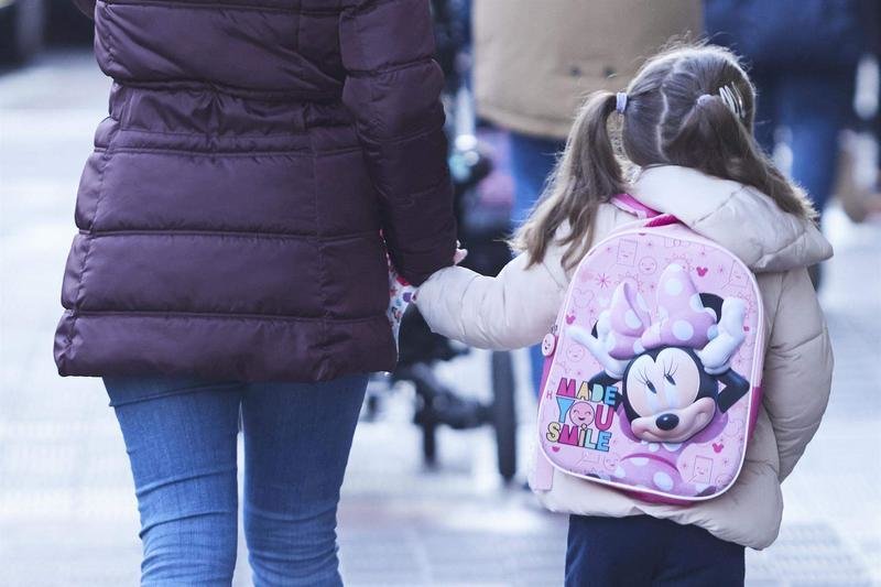 <p> Una niña, acompañada de un madre, durante la vuelta al colegio de los niños </p>