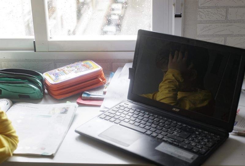  Reflejo en un ordenador portátil de un niño estudiando 