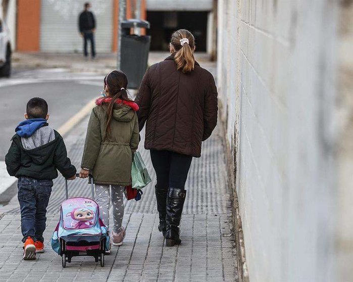  Un niño y una niña, acompañados de una mujer, caminan hacia el colegio público CEIP Antonio Machado 