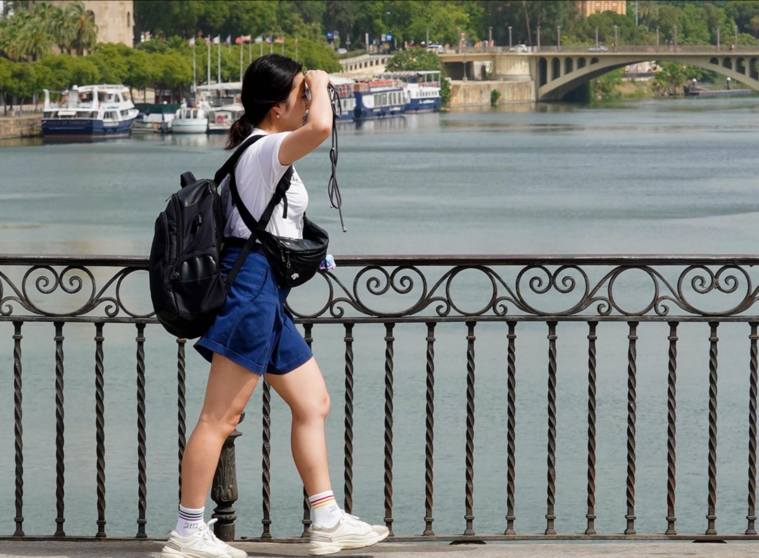  Una persona paseando por el Puente de Triana se protege la cara el día en que la capital está en alerta naranja por el calor , a 19 de julio del 2023. - Eduardo Briones - Europa Press 