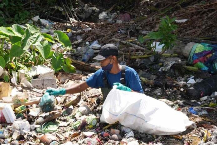  Personal de Sungai Watch limpiando la basura plástica recogida en las barreras del río. Imagen cortesía de Sam Benchegjib 