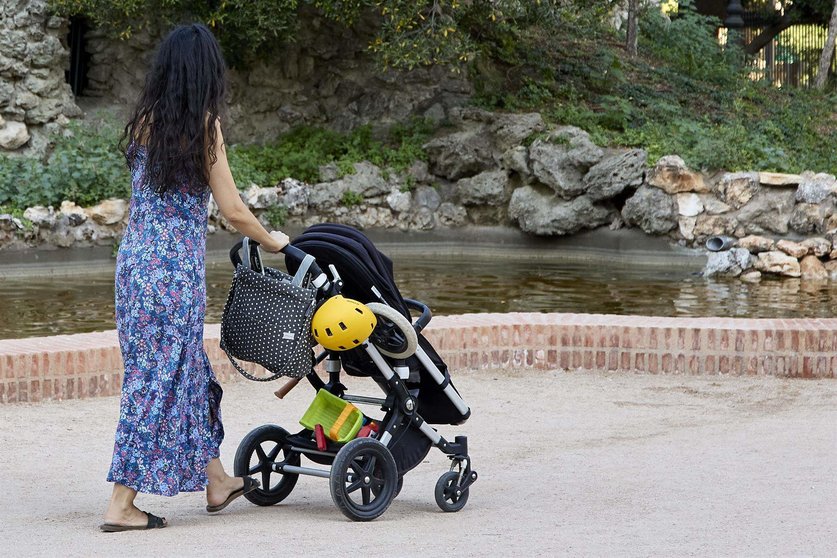  Una persona pasea con un carrito de bebé en el parque de El Retiro 