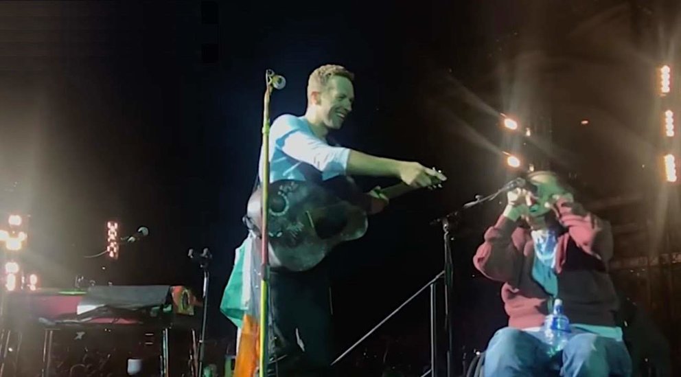  Chris Martin durante su concierto con uno de sus fans en el escenario | YouTube. 