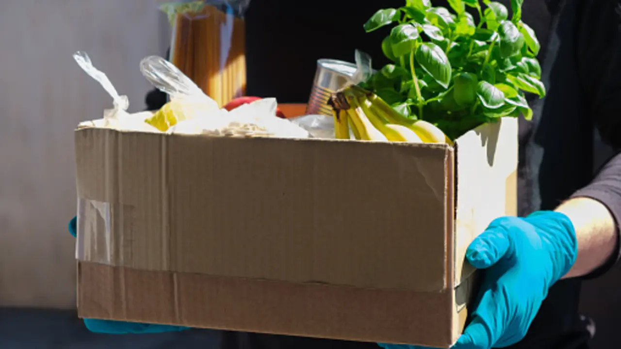 Home delivery during an epidemic. contactless delivery. Food donation. Men's hands hold a box with products