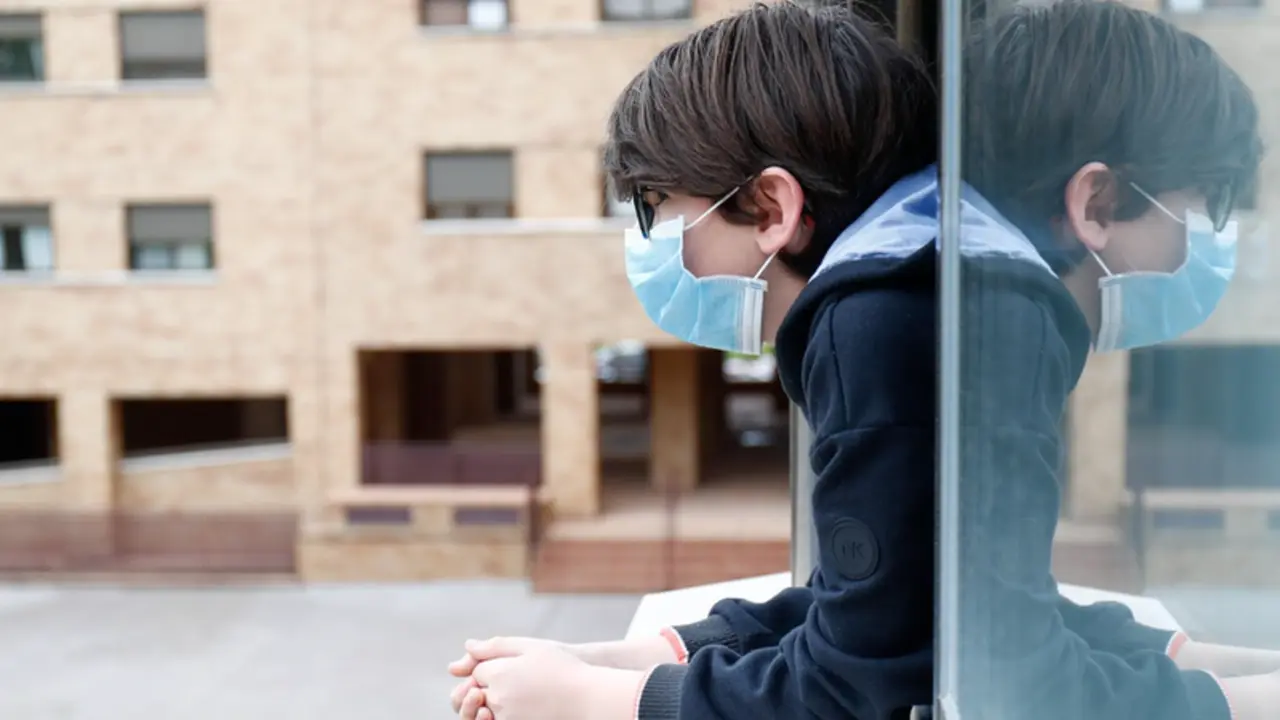 Archivo - Un ni&ntilde;o con una mascarilla se asoma a la ventana de su casa. - &Oacute;scar J.Barroso - Europa Press - Archivo 