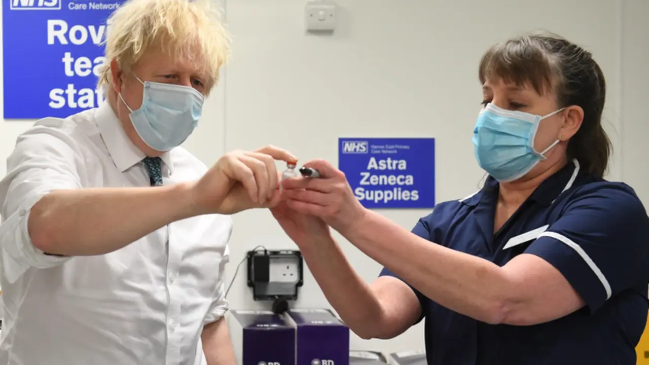  25 January 2021, United Kingdom, London: UK Prime Minister Boris Johnson (L) is shown a vial of the Oxford/Astrazeneca COVID-19 vaccine during a visit to Barnet FC's ground at The Hive, which is being used as a coronavirus vaccination centre. - Stefan Rousseau/PA Wire/dpa 