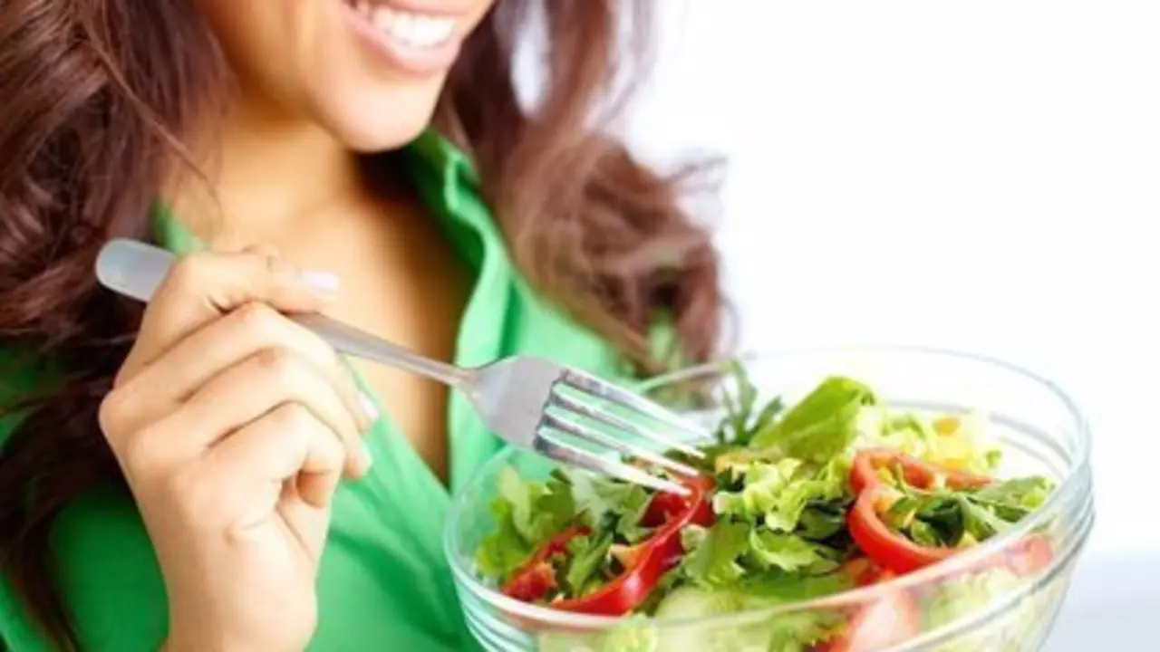 Close-up of pretty girl eating fresh vegetable salad