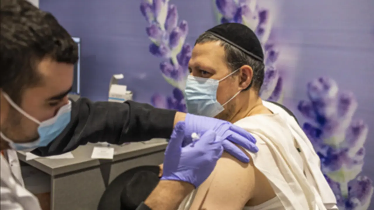  Un jud&iacute;o ortodoxo recibe su dosis de la vacuna Pfizer-BioNTech COVID-19 en un centro de vacunaci&oacute;n como parte de una campa&ntilde;a nacional. 