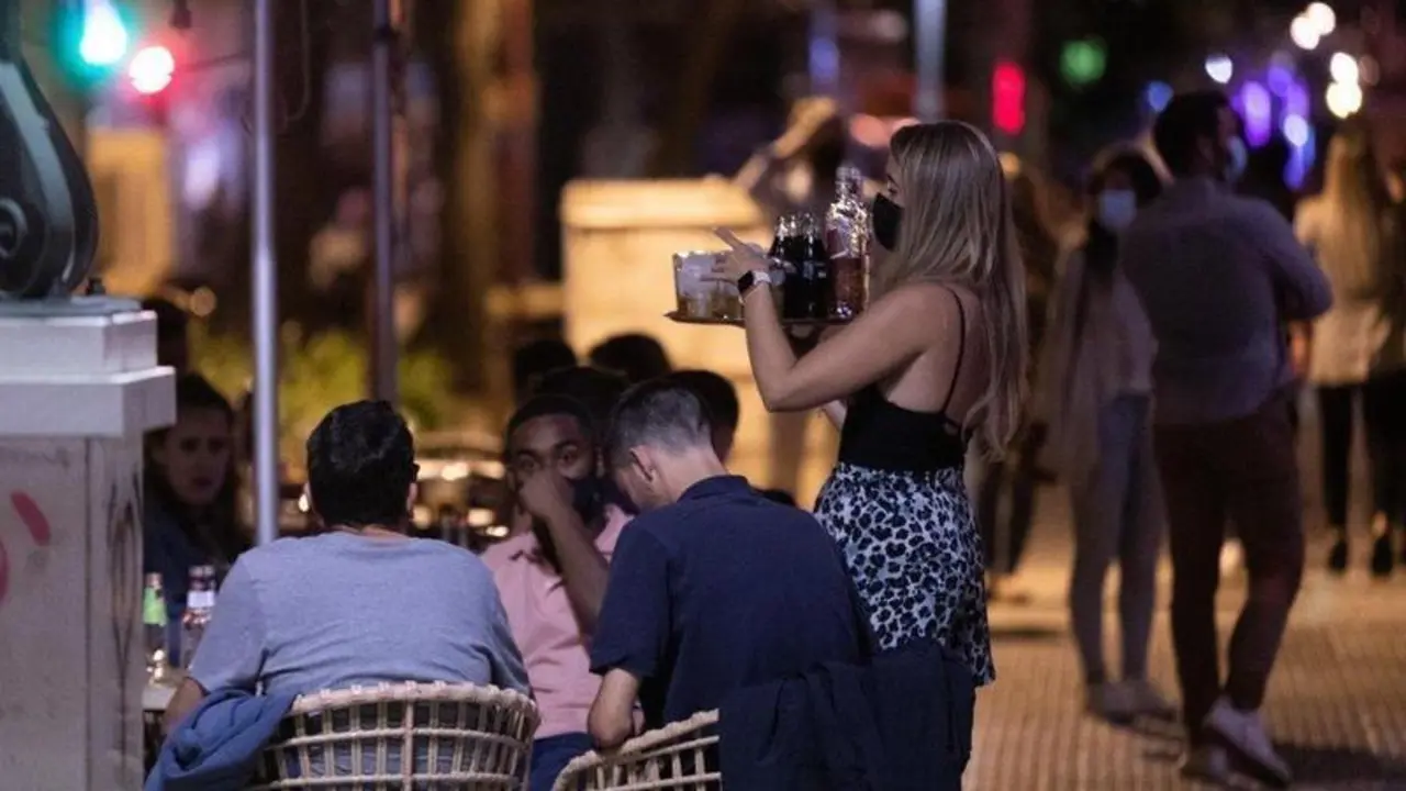  na camarera atiende a varias personas en la terraza de un bar 