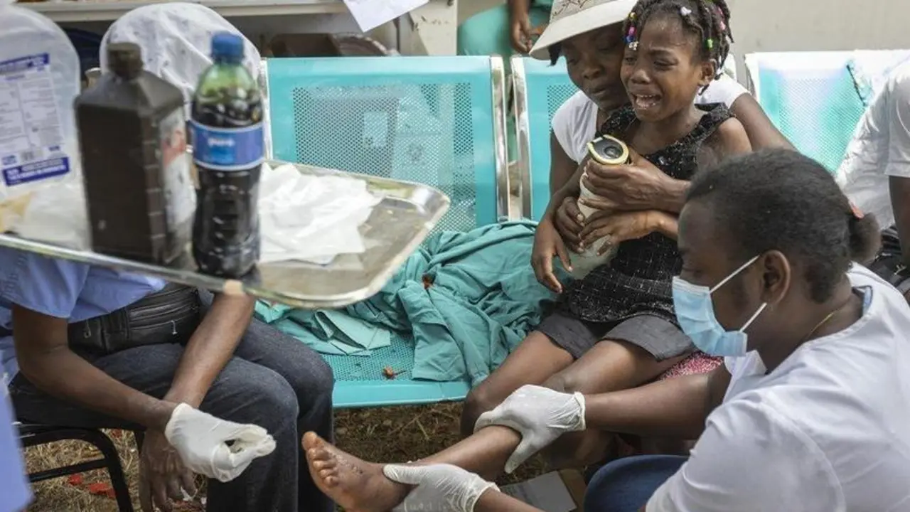  16 August 2021, Haiti, Les Cayes: A young girl is held by her mother as nurses care for a wound on her foot at OFATMA Hospital, as the patients afraid of hospital collapse after it's walls and floor cracked during the earthquake. Rescuers in Haiti are wor - Jose A. Iglesias/TNS via ZUMA Pr / DPA 