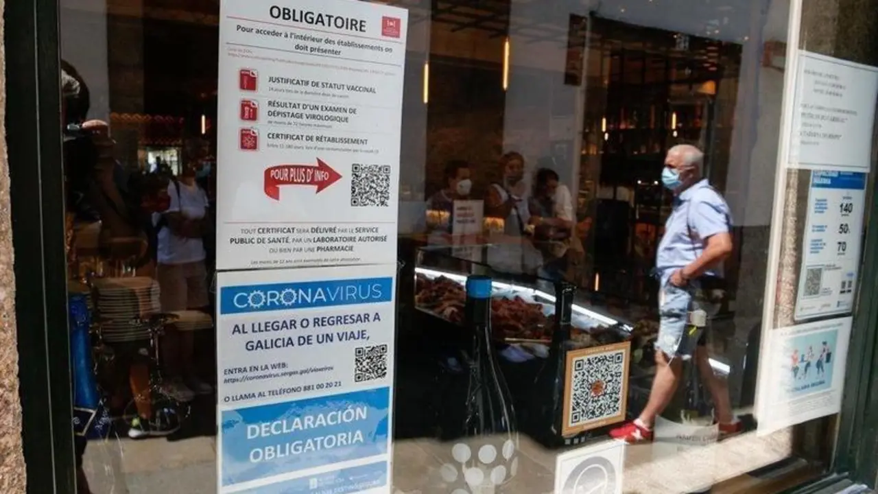  Carteles en diferentes idiomas de indicaciones de obligatoriedad de presentar certificados antes de acceder al interior, a 12 de agosto de 2021, en Santiago de Compostela, A Coru&ntilde;a, Galicia (Espa&ntilde;a). - C&eacute;sar Arxina - Europa Press 