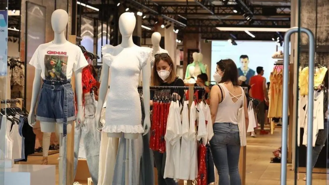 <p> Personas en una tienda de ropa con la mascarilla puesta </p>