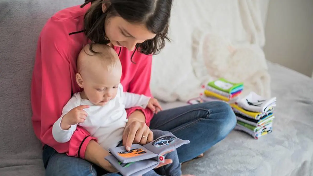 <p> Una madre con su beb&eacute; mirando un libro infantil. </p>