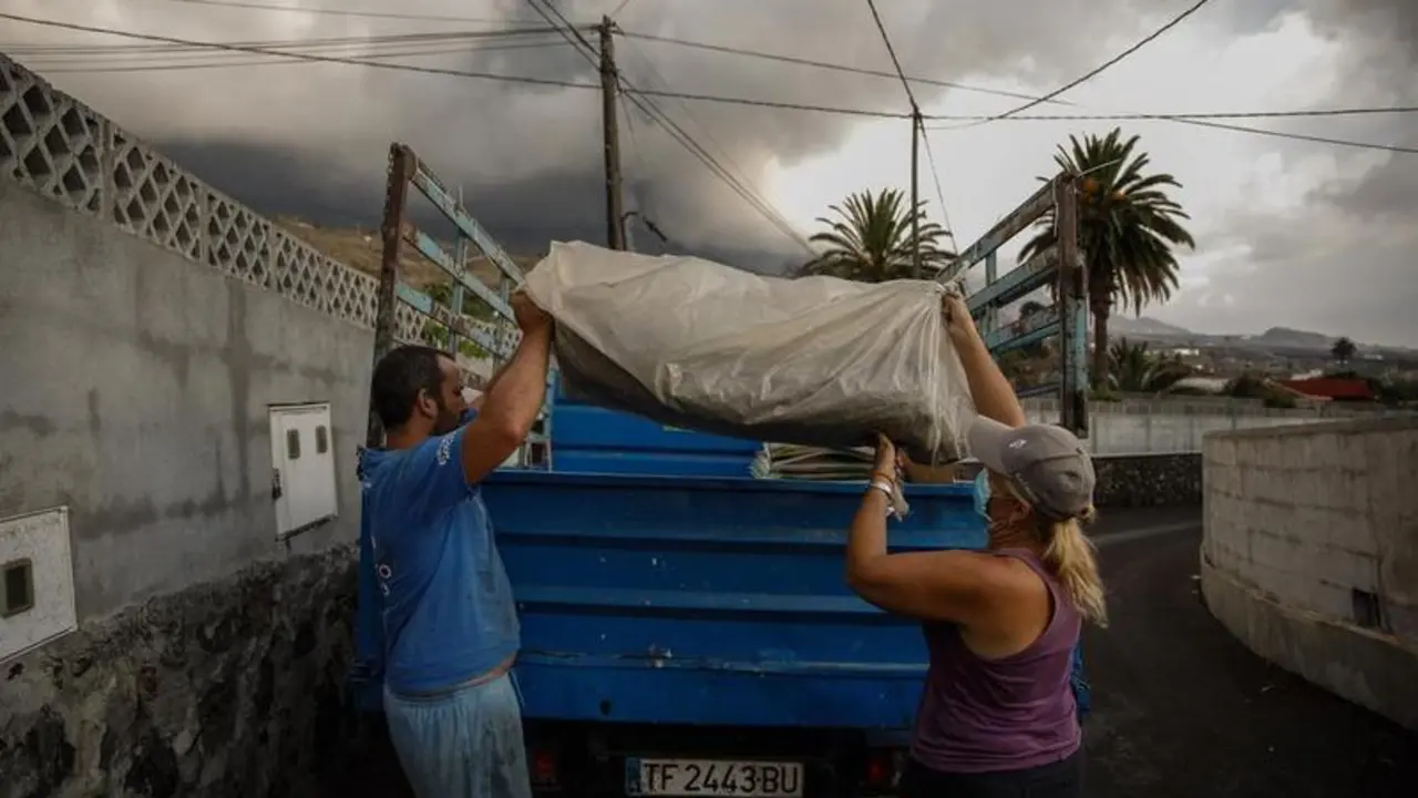 <p> Un hombre y una mujer sacan sus pertenencias de su casa por la actividad del volc&aacute;n de &lsquo;Cumbre Vieja&rsquo; </p>