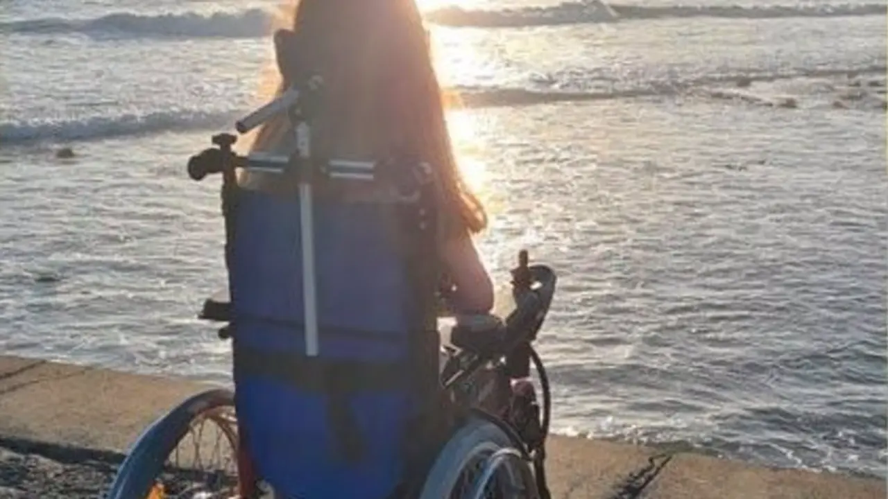 <p> Una joven en silla de ruedas mirando al mar. - CHANGE.ORG </p>