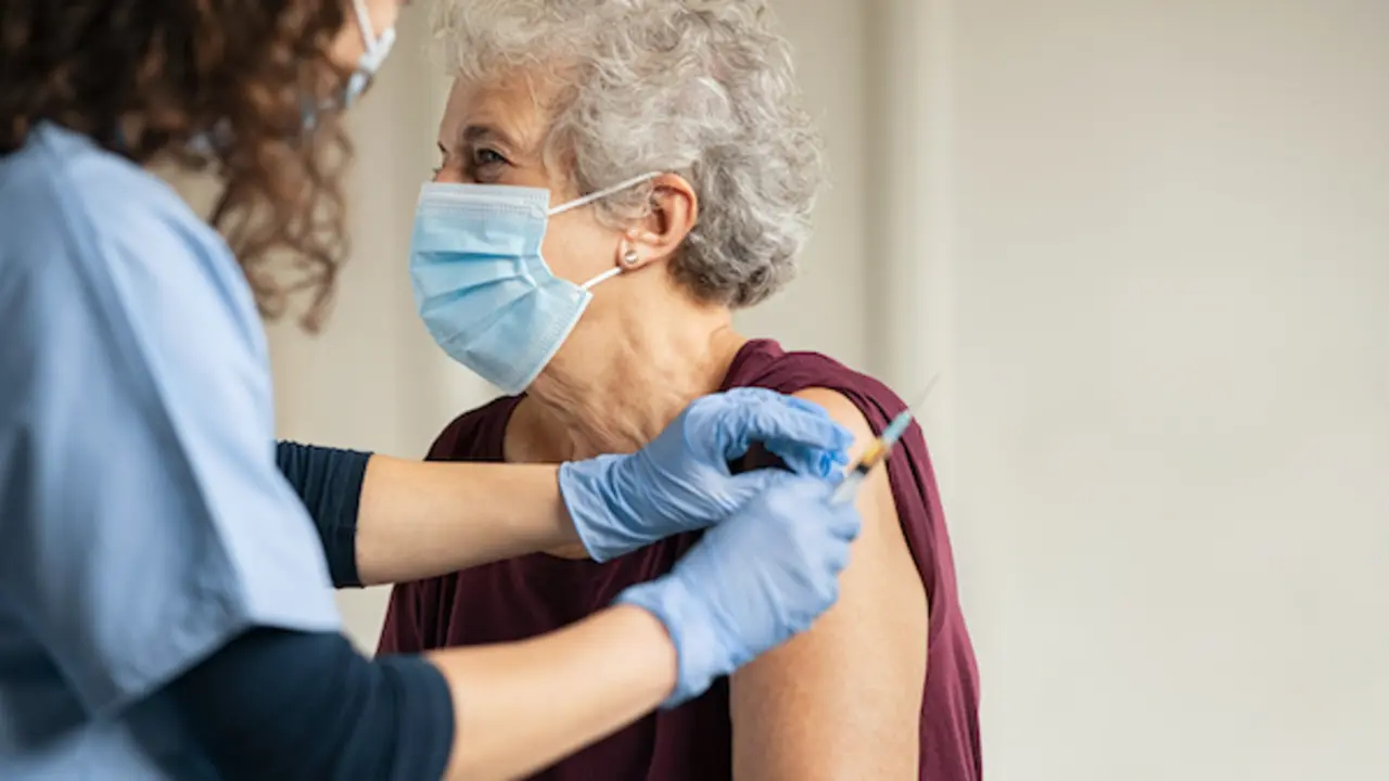 General practitioner vaccinating old patient in private clinic with copy space. Doctor giving injection to senior woman at hospital. Nurse holding syringe and using cotton before make Covid-19 or coronavirus vaccine.