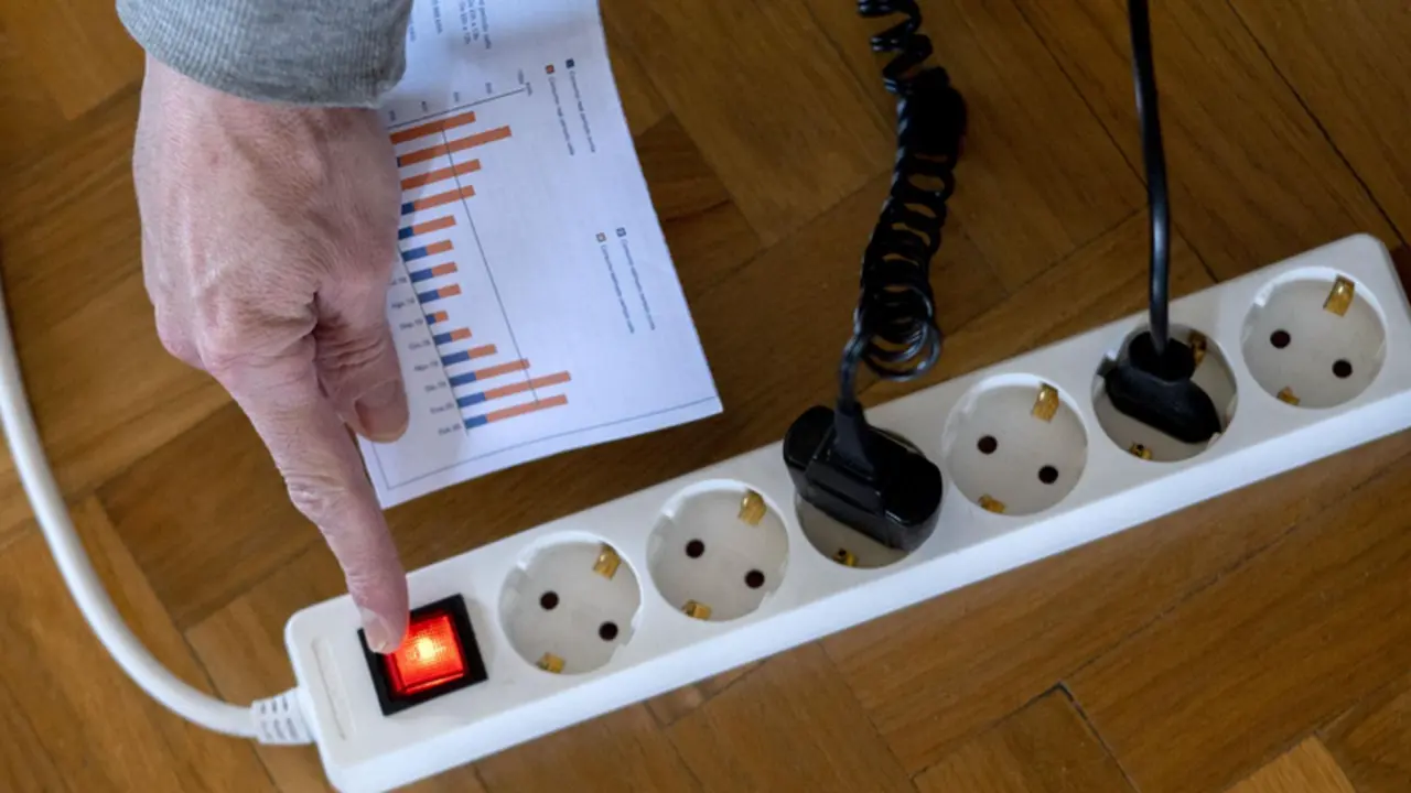 <p> Un hombre enciende una largadera con varios enchufes con una factura de luz en la mano. - Alberto Ortega - Europa Press </p>