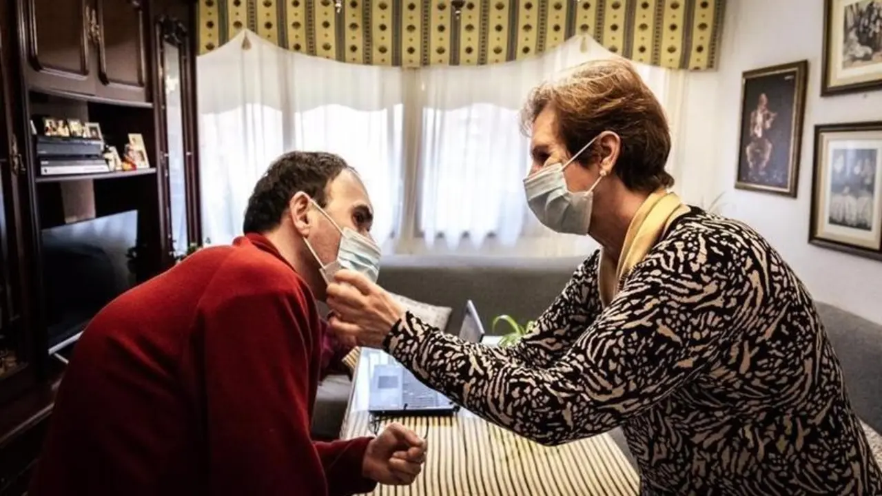 <p> Archivo - Una mujer ayuda a su hijo con discapacidad a colocarse la mascarilla. - ROBERTO PALOMO - Archivo </p>