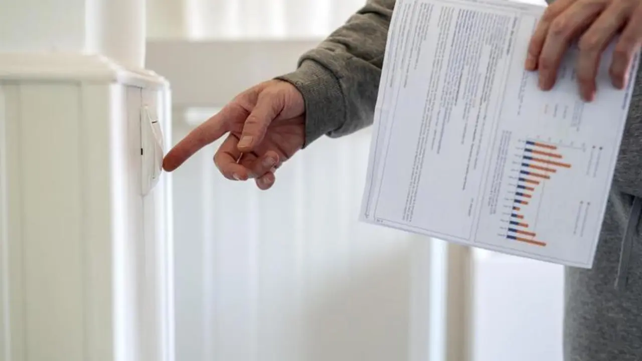 <p> Un hombre enciende un interruptor con una factura de luz en la mano, a 3 de enero de 2022 </p>