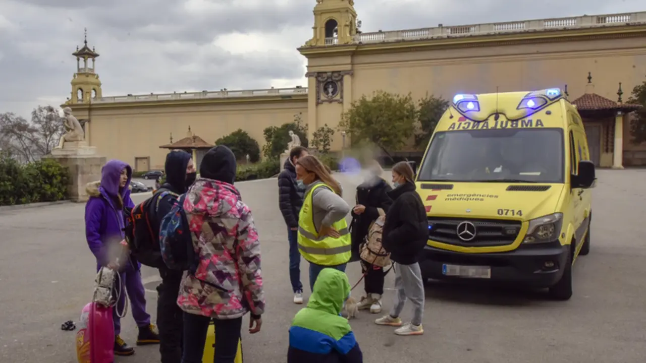 <p> Varios refugiados y una traductora, junto a una ambulancia, en la entrada del palacio de Victoria Eugenia, el palacio 7 de Fira de Barcelona, convertido en un centro de recepci&oacute;n - David Oller - Europa Press </p>